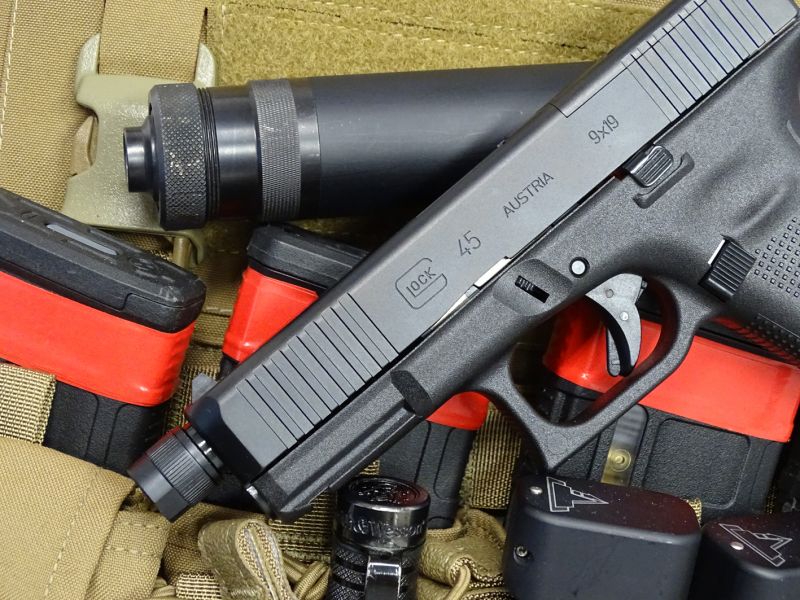 Pěkné zátiší s inovovaným Glockem 45 MOS a s prodlouženou hlavní s integrovaným závitem na jejím ústí. Logo společnosti, číselné označení, země původu i označení ráže jsou z důvodu předních hmatníků posunuty poněkud více vpravo.