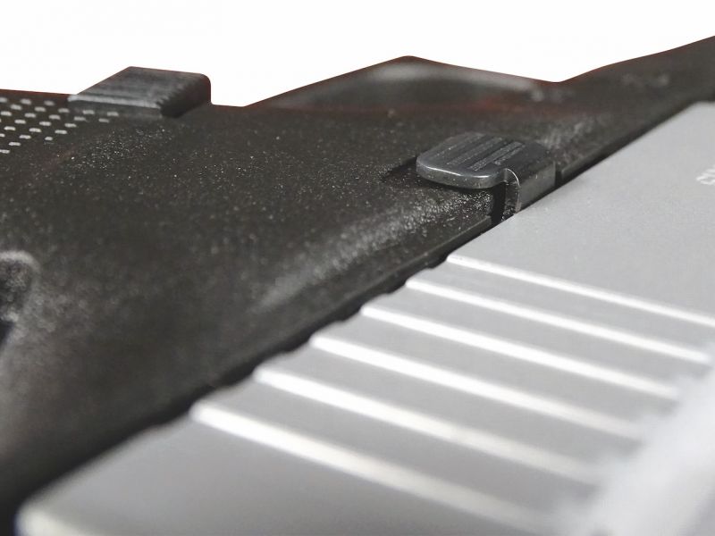 Detailní záběr odhalující ono zmiňované rozšíření boční stěny pistolové rukojeti, které si také vyžádalo úpravu ovladače záchytu závěru – jeho krček je prodloužený.