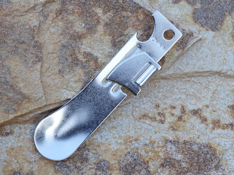 Otevírač konzerv Highlander. Funguje bezproblémově a navíc má ve své konstrukci integrovaný otevírač korunkových uzávěrů a také nouzovou lžičku. Délka otevíráku je 90 mm a hmotnost 16 gramů. Konstrukčně jde o poniklovanou ocel. Cena cca 85,- Kč za dvojici otevíráků.