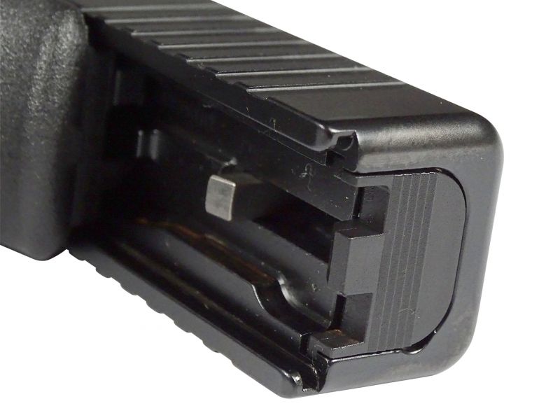 Detailní pohled v nadživotní velikosti na zadní část závěru s odstraněným zadním krytem. To nám umožňuje nahlédnout do samotného nitra největší ocelové součásti pistole. V detailu jsou pak pěkně vidět také vodící drážky – často opomíjená konstrukční součást pistole bez které by však pistole byla úplně k ničemu.