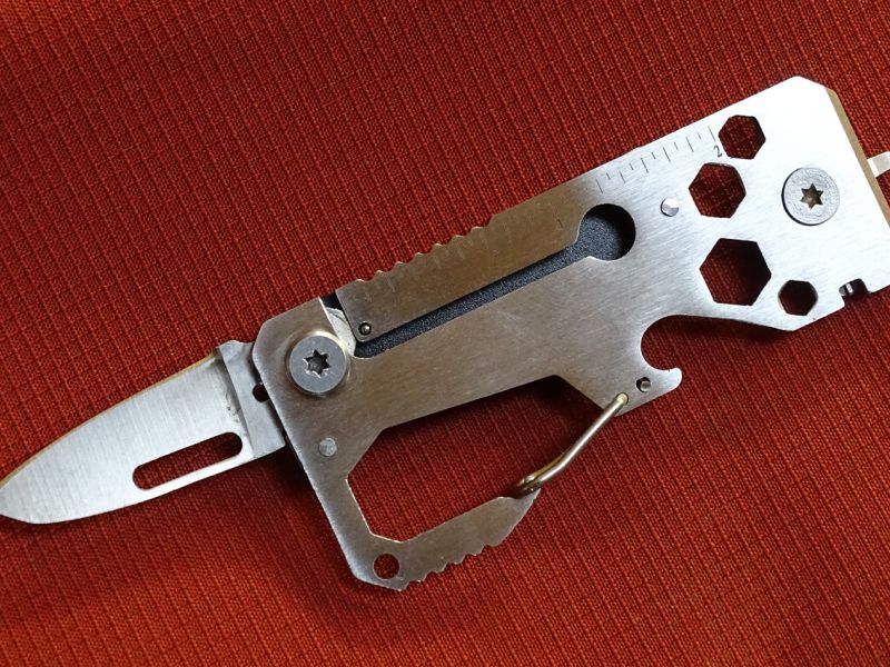 Multitool s otevřeným nožíkem z rubové strany. Nástroj je celý (vyjma úchopové střenky) vyroben z nerezové oceli. Na tomto pohledu je také pěkně vidět umístění klíčů a otevíráku korunkových uzávěrů.