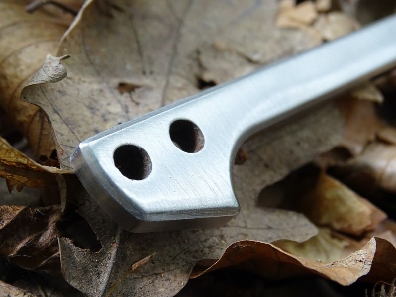 Otvory pro pojistnou či závěsnou šňůru v zadní části nože.